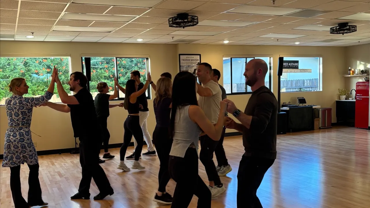 Adults practice partner dancing together during a studio class.