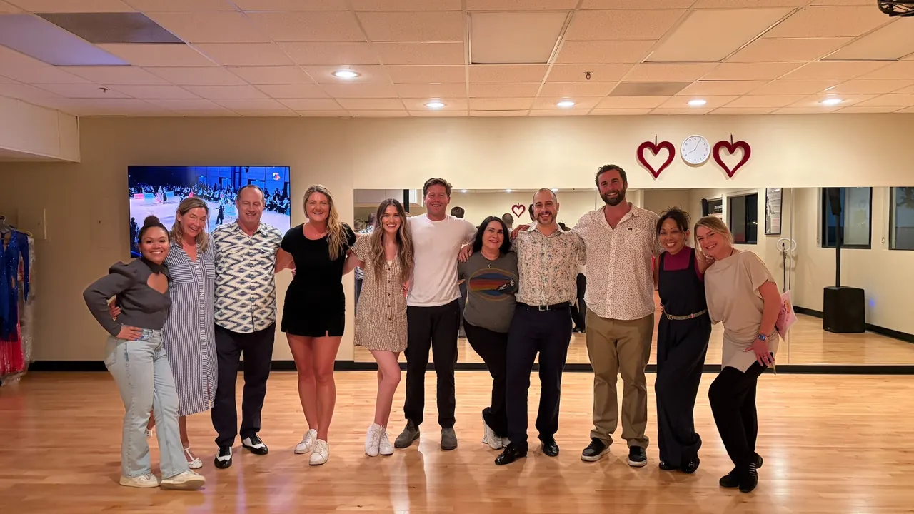 A smiling group of adults gathers together on the studio floor.